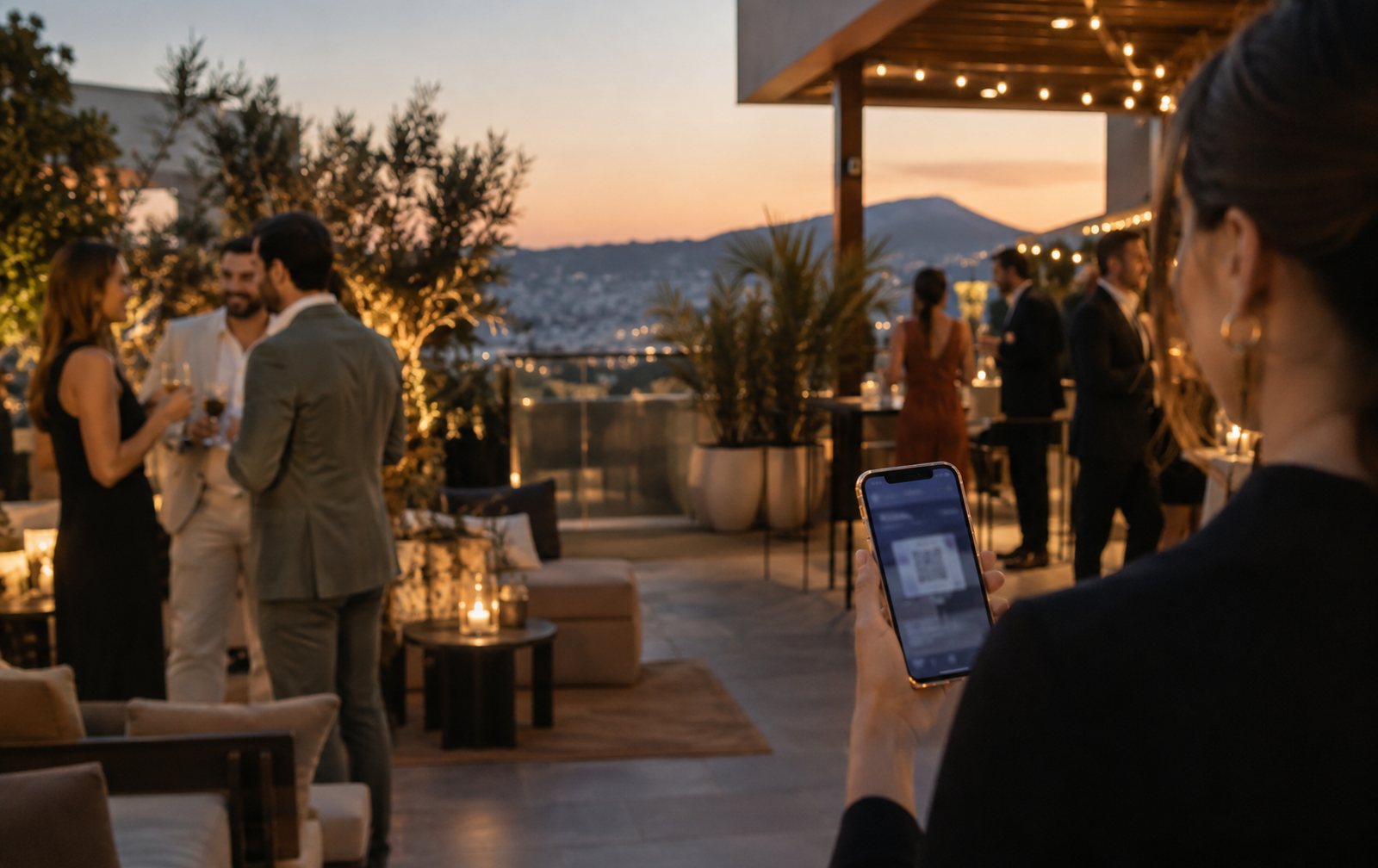 Terraza de evento al anochecer con luces cálidas y un móvil mostrando entradas digitales